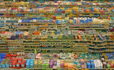 Image looking down on a large supermarket type store - looking across the tops of multiple aisles, showing huge amounts of multi-coloured products with printed labels and packaging on.