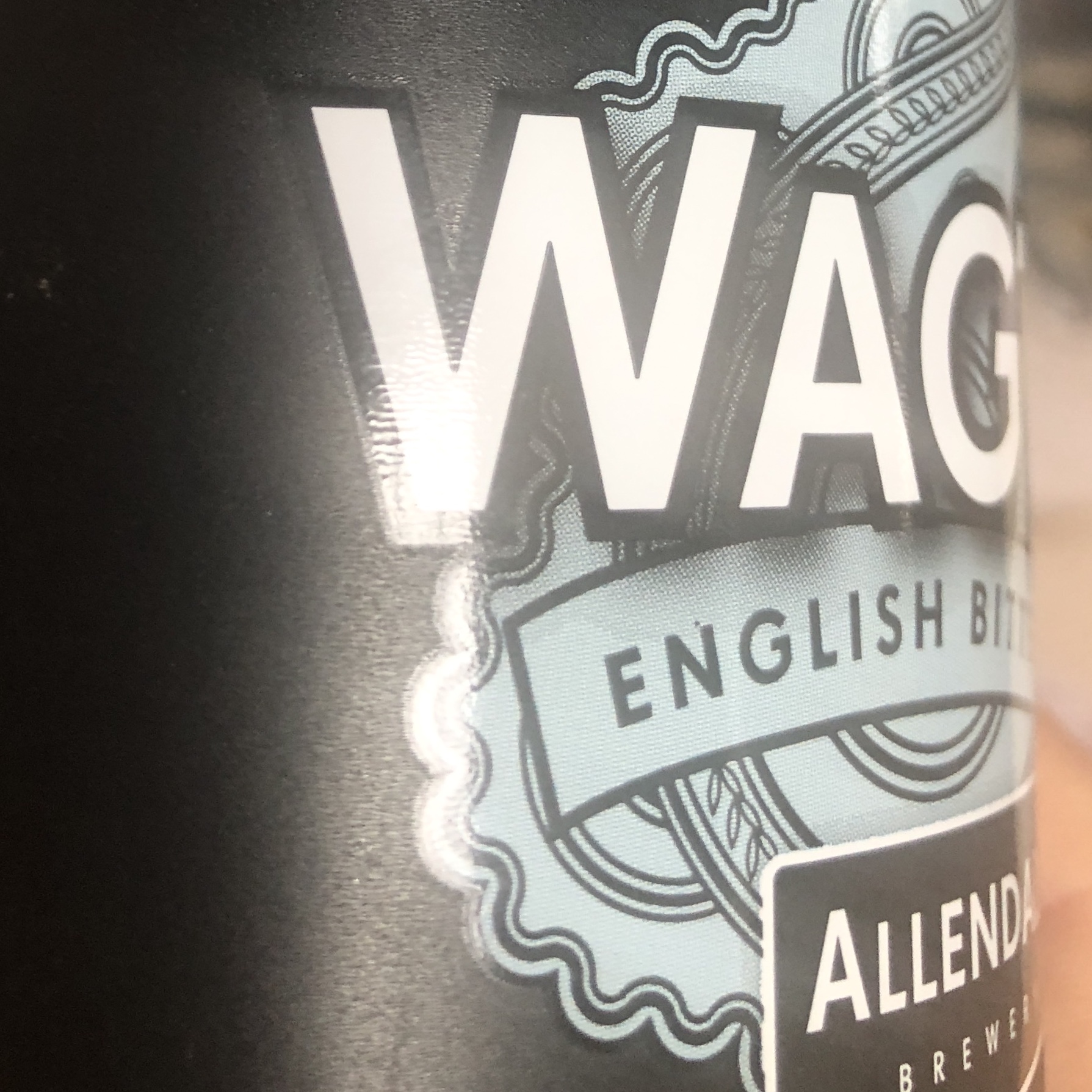 Close up image of a beer bottle label with the letters 'WAG' visible at the top, with this area having been spot varnished. Beneath this are the letters 'ENGLISH BIT' - with the rest of the word not visible