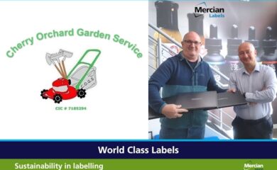 A rectangular image with the logo for Cherry Orchard Garden Service on the left hand side which incorporates a cartoon style bright red lawn mower with a bright green handle and a garden shovel, rake and hoe propped up behind it, whilst on the right hand side is a photo of two white, shaven headed men (one wearing jeans and navy blue and dark green fleece jacket and the other wearing business suit trousers and a blue and white striped shirt) smiling and facing the camera as the three laptops are handed over.