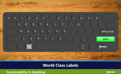 Image shows a black keyboard sat on a wooden surface, but instead of the usual characters (in white text) on the keyboard each button spells out: T: 01543 431070 CONTACT MERCIAN LABELS. There are then three large buttons to the right hand side. The first states ‘Shift up a level’, below that, the largest button is bright green and has the word ‘Start’ written on it in Black and below that is a button with the Mercian Labels logo on it. To the left of the space bar is a button with a QR code on it which links to the Mercian Labels website.