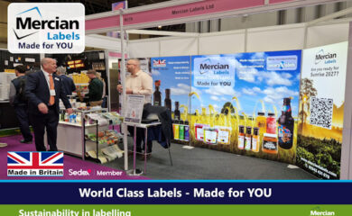 Exhibition stand for Mercian Labels featuring large, brightly lit, branded displays with the slogan “World Class Labels - Made for YOU.” The stand showcases sample product labels on bottles, jars and packaging, with messaging about sustainability and British manufacturing. Two men in business attire stand and converse beside a display table of printed labels. The image includes a Made in Britain logo, Sedex Member logo and a QR code panel asking “Are you ready for Sunrise 2027?”