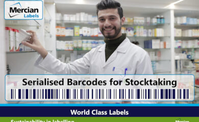 A smiling pharmacy worker wearing a white lab coat places a medicine box on a shelf in a bright pharmacy stocked with medications. The image is branded with the Mercian Labels logo in the top-left corner. Across the lower middle of the image, large text reads “Serialised Barcodes for Stocktaking” above a prominent barcode graphic. A dark blue banner at the bottom states “World Class Labels,” with a green section below referencing sustainability in labelling and a “Mercian zero” logo in the corner.